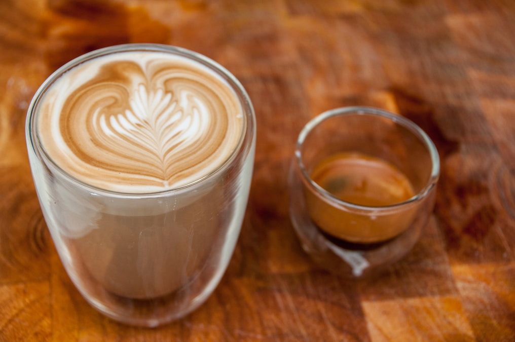 regular latte in glass next to espresso shot in glass