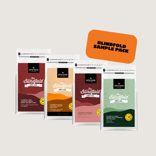 four bags of coffee beans with modern logos showcasing a Blindfold sampler offering of organic arabica coffee
